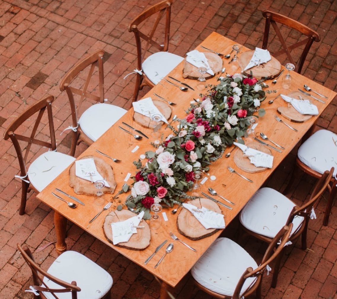 Mesas rectangulares de madera maciza decoradas para boda en entorno natural.