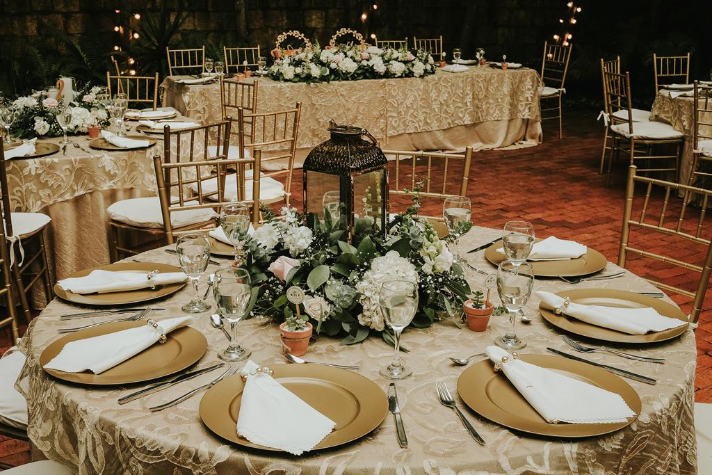 Platos base plateados reflejando luz cálida en salón de recepción Casa Aragón.