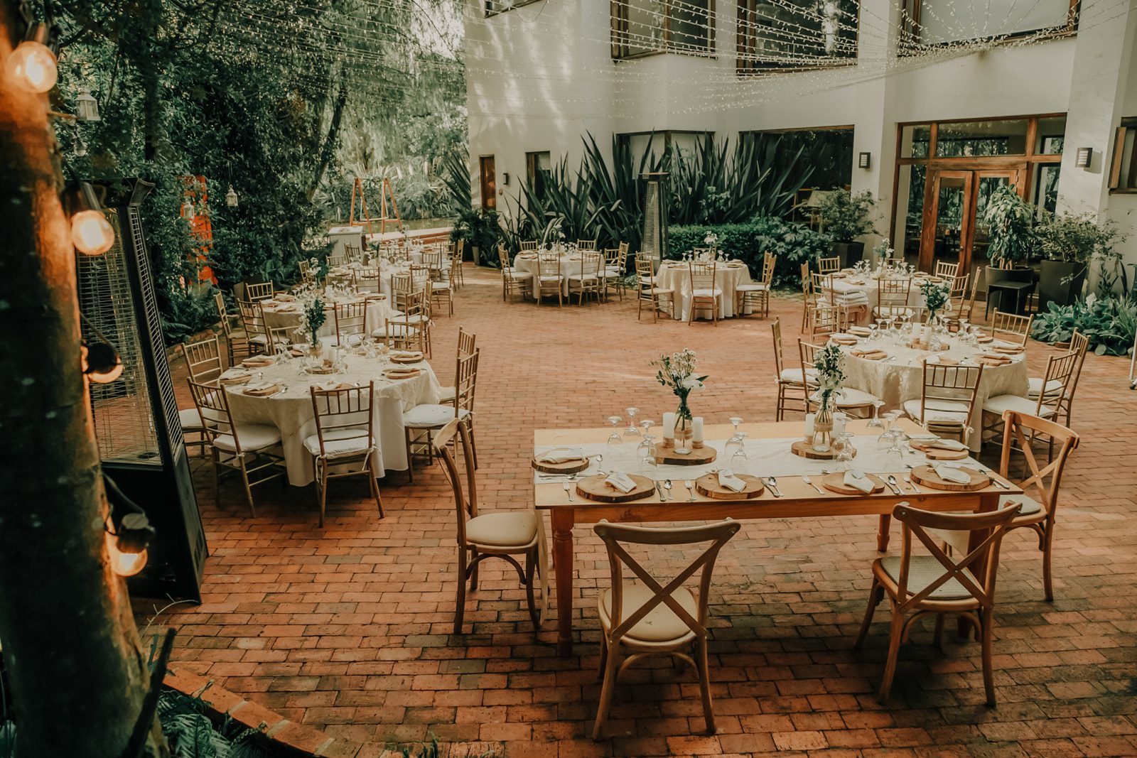 Sillas Crossback de madera alrededor de mesa decorada para cena de matrimonio en Casa Aragón.