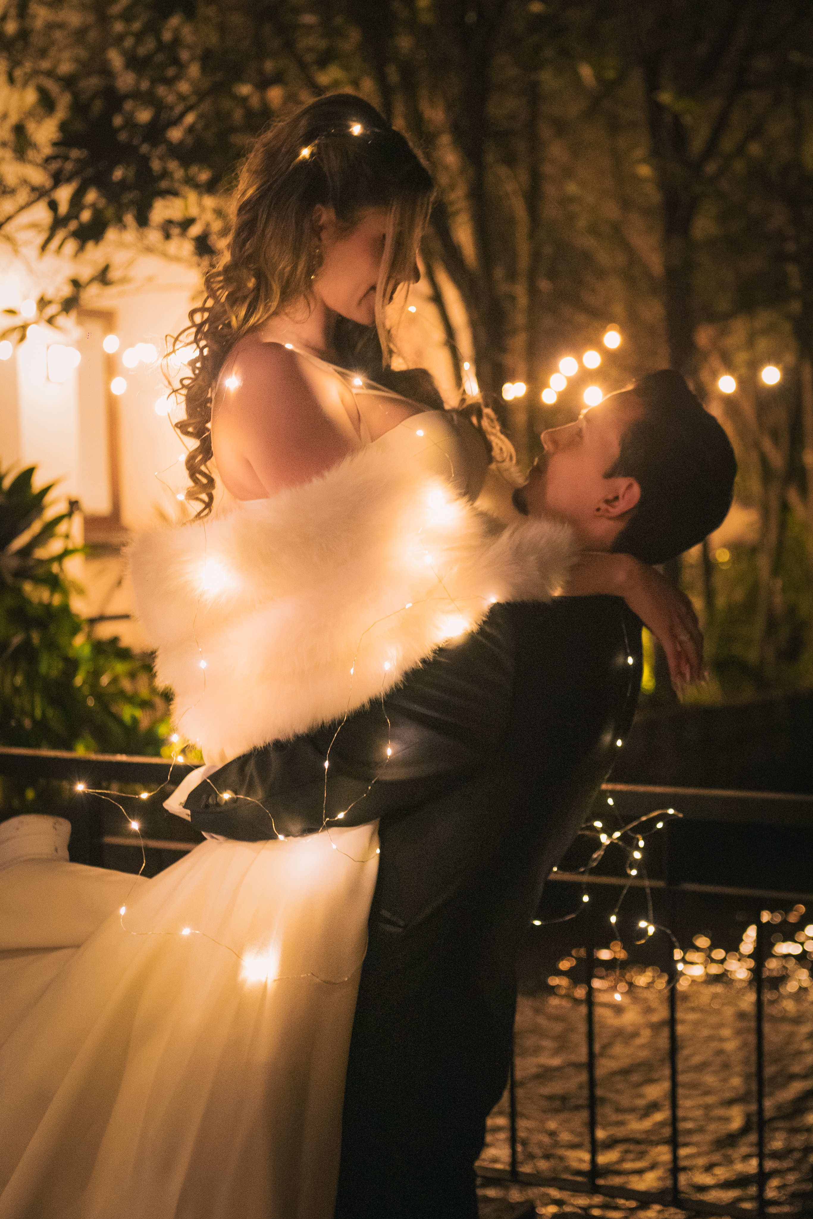Pareja posando en la Terraza del Lago de Casa Aragón decorada con luces cálidas.